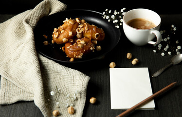 donuts with caramel and hazelnuts, cup of coffee on the rustic table