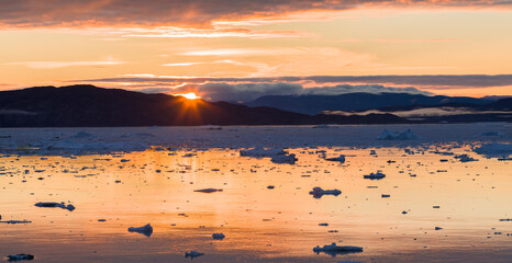 Sunset over fjord with icebergs close to Eqip Glacier in Greenland, Danish Territory.