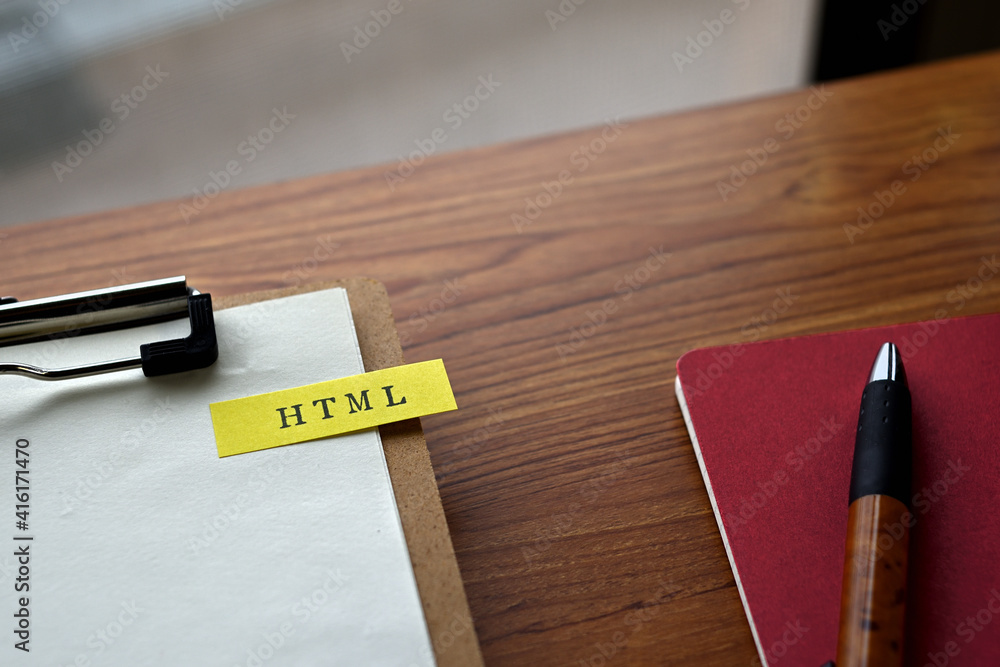 Poster there is a notebook, a pen, and a clipboard with a sticky note stuck to it that says html written on