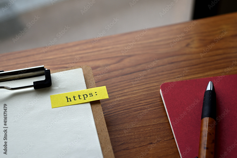 Poster there is a notebook, a pen, and a clipboard with a sticky note stuck to it that says https: written 