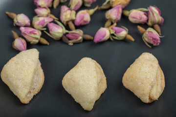A dark plate full of dried roses and pastries
