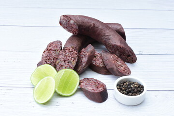 Morcilla Antioqueña, traditional Colombian sausage, covered with lemon and pepper on wooden background
