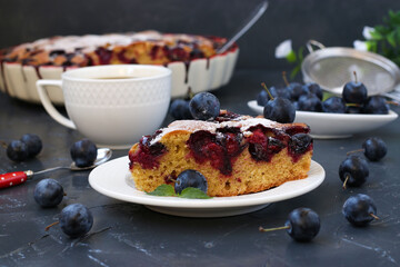 Piece of cake with blackthorns berries and cup of coffee on dark background