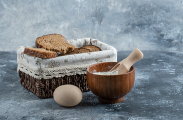 Slices of brown bread on a basket on a gray background