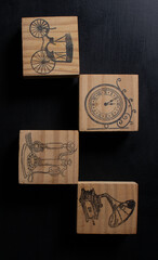 Four pieces with different handicraft paintings representing a clock, a carriage, an old telephone and a record player. They are on a gray wooden table with lighting that transcends horizontally.