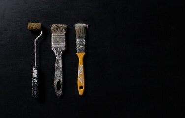 Brushes for handmade painting with different sizes and colors, predominantly yellow. They are on a gray wooden table used in making crafts with lighting that transcends horizontally.