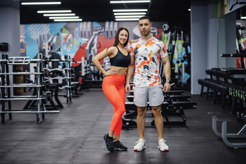 Fit sporty couple standing in gym and posing. Bodybuilding, healthy habits, indoor fitness