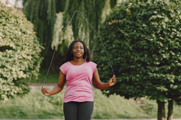 Healthy young african woman outdoors in morning. Girl with a rope.