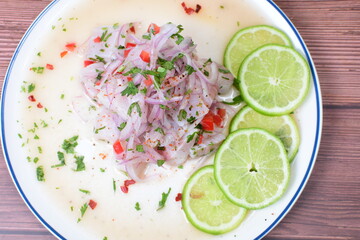 Traditional Peruvian ceviche with fish, onion, lemon, chili peppers, coriander, salt and pepper on wooden background