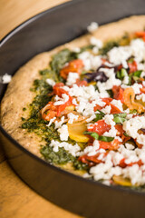 Grated mozzarella cheese on a homemade unbaked, vegetarian, multi-grain thick-crust pizza.