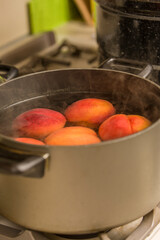 Peaches in a pot of boiling water that are being blanched, after which they will be immediately put into ice cold water, to be able to easily remove their skins prior to canning.