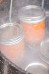 Jars of apricot jam resting on a canner rack in a boiling water canner. Canner racks simplify the...