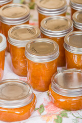Jars of freshly homemade apricot jam cooling on a tea towel without touching or bumping in a draft-free place.
