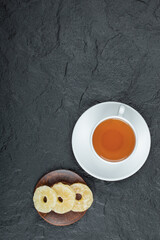 A cup of aroma tea with dried pineapple on a dark background