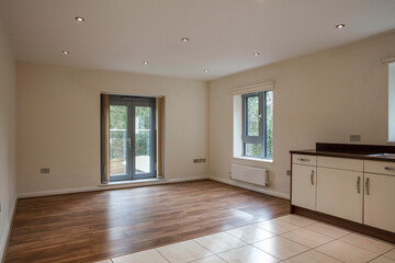 View of an empty living room area in a modern apartment with wooden flooring