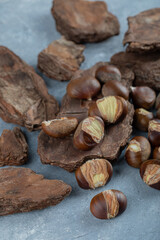 Roasted chestnuts on marble background with wood pieces