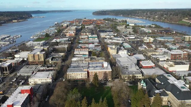 Cinematic aerial orbiting drone view of commercial and residential areas, stores and businesses downtown, in the historic district of Olympia, Port of Olympia, Pierce County, Washington