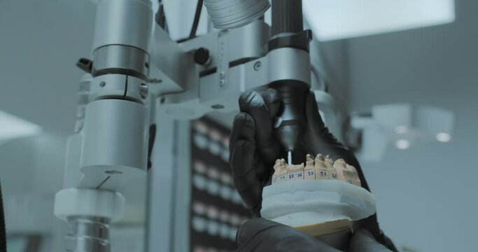 A dental technician is polishing screws inside the dental prothesis with a special equipment.