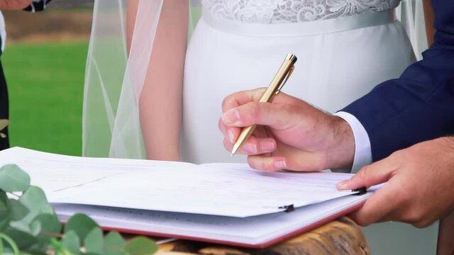 Groom signing the official Wedding Certificate - close up