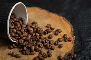 A black cup full of coffee beans on a wooden board