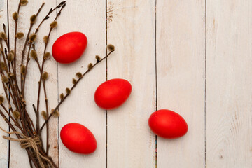 Red easter eggs on white wooden table with branch of willow. Easter backgrounds with copy space for text. Top view. Greeting card. Happy easter concept.