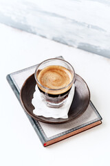 Coffee in glass cup on bright wooden background.	