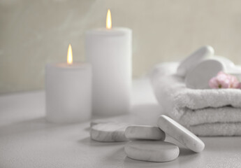 Spa stones, towel and candles on white table
