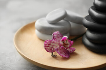 Spa stones and orchid flower on grey table, closeup