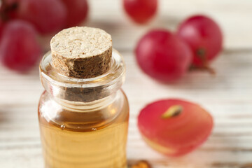 Bottle of natural grape seed oil on white table, closeup with space for text. Organic cosmetic