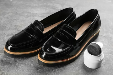 Shoe care product and footwear on grey stone table, closeup