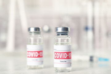 Vials and syringe with coronavirus vaccine on light table