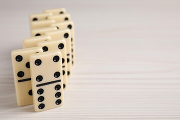 Domino tiles on wooden table, closeup. Space for text