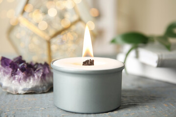 Burning candle with wooden wick on grey table