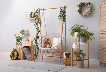 Easter photo zone with floral decor and swing chair indoors - Powered by Adobe