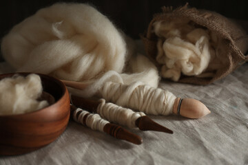 Soft white wool and spindles on table, closeup