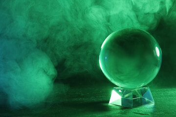 Crystal ball on table and smoke against dark background, space for text. Predictions of future