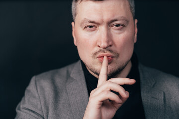 Serious business man showing silence gesture