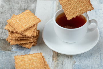 A cup of aroma tea with crackers on a wooden table