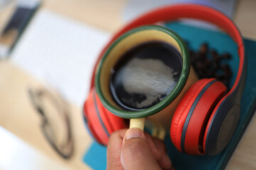 The work desk has a coffee cup and red headphones and office supplies.