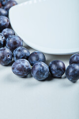 Group of fresh plums around the white plate