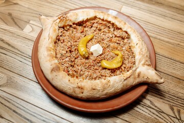 Top view on tasty traditional Adjarian Khachapuri - open baked pie with meat and pepperyolk on wooden tray. Traditional georgian food