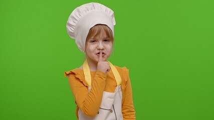Child girl kid dressed as professional cook chef holding finger on her lips on chroma key background. Gesture of shhh, hush, secret, silence. Nutrition, cooking school, education, food. Fun and humor