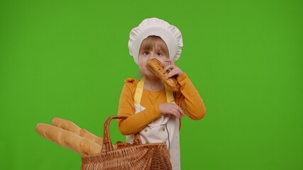 Child girl dressed in apron like chef cook showing basket with baguette and bread, smiling,...