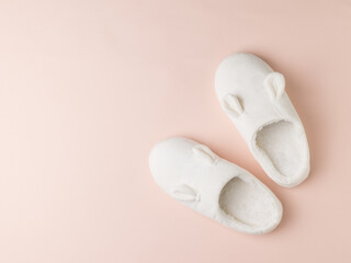 Stylish white house slippers on a light pastel background. Top view. Flat lay.