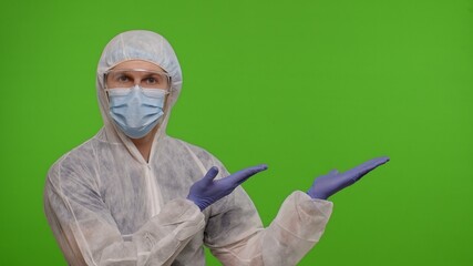 Medical doctor in protective PPE suit pointing at right on blank space on chroma key background. Copy-space. Place for your advertisement logo. Concept of vaccination against coronavirus covid-19