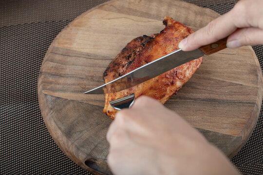 Female Hands Cutting Chicken On Wooden Board