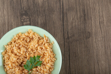 Delicious bulgur with greens on a green plate