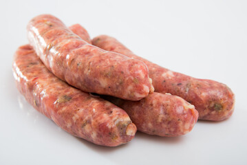 Appetizing uncooked meat sausages with mushrooms on white surface