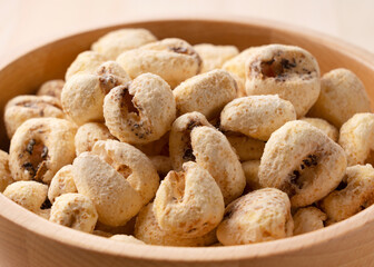 Jumbo corn baked goods in a wooden bowl set against a wooden background