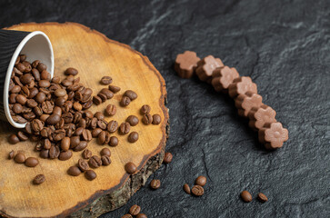 A black cup full of coffee beans on a wooden board